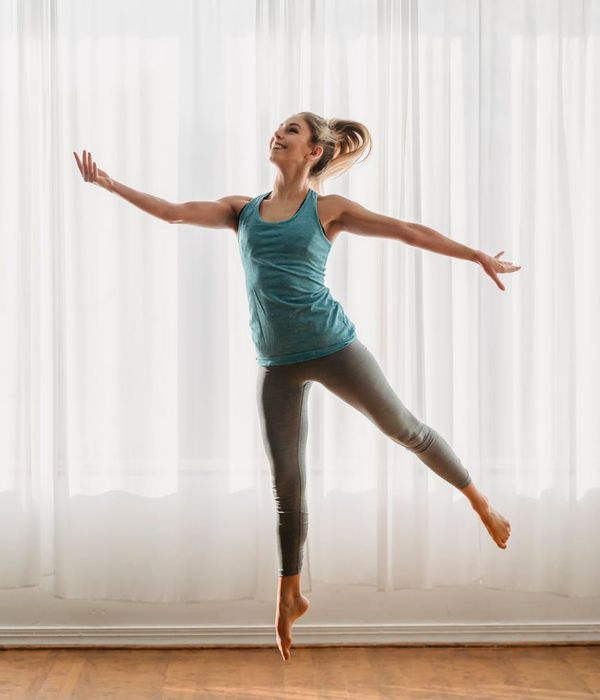 Woman performing a light, dynamic exercise in a bright, airy room.